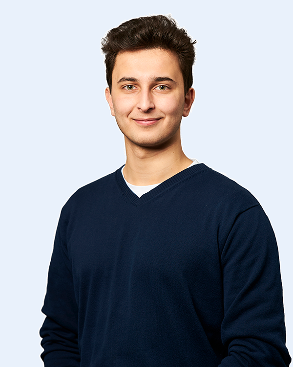 Lächelnder junger Mann im dunkelblauen Pullover, Frontporträt vor hellem neutralem Hintergrund
