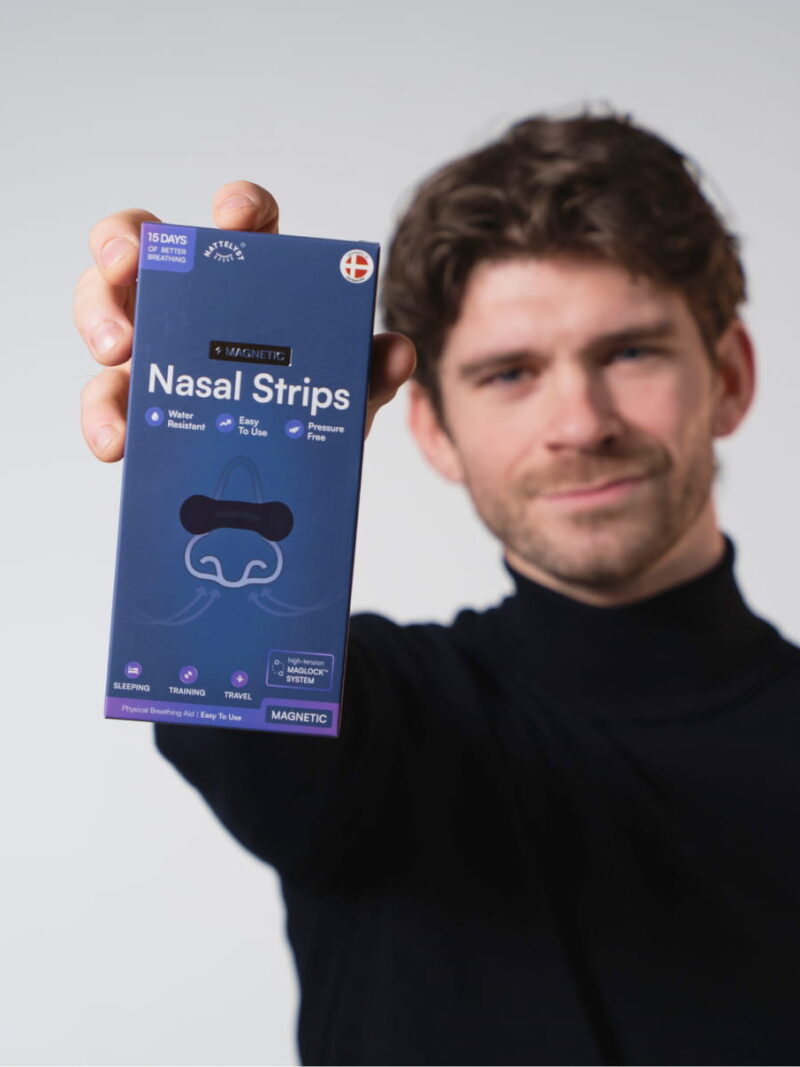 Mann hält eine blaue Packung magnetischer Nasenpflaster, Nahaufnahme von Produktname und Verpackung
