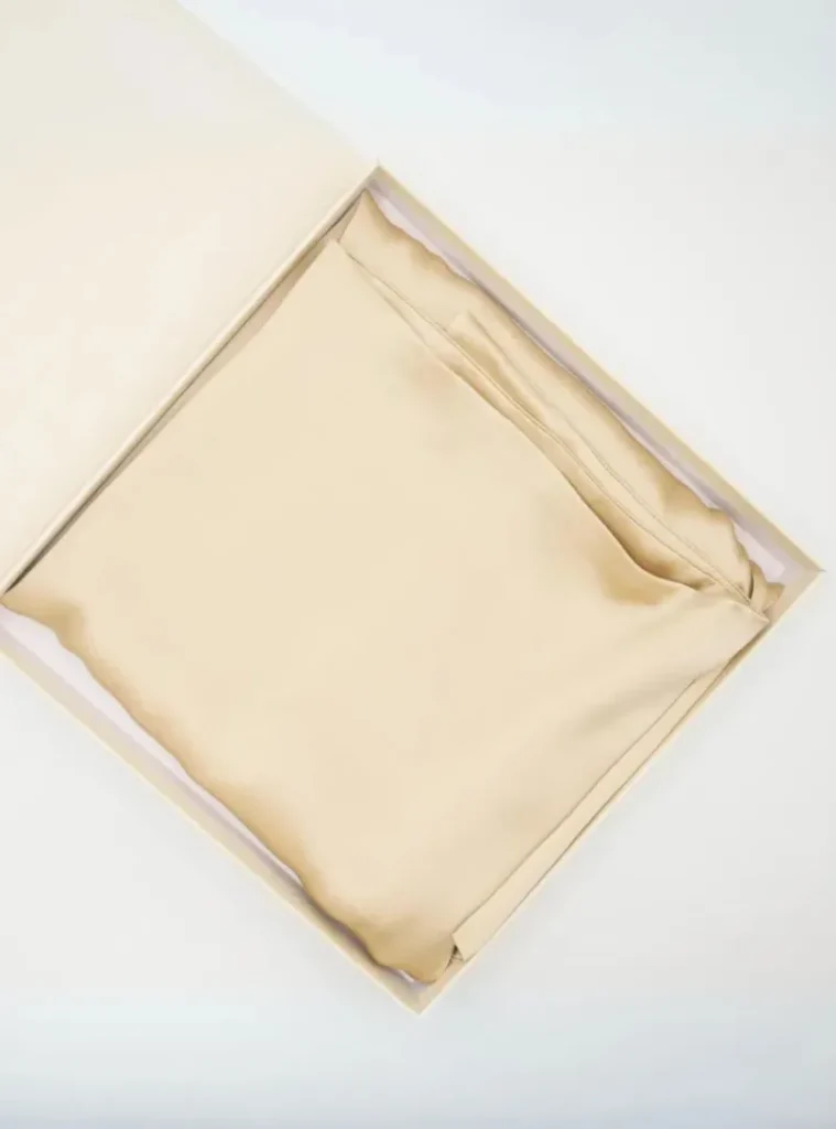 Beigefarbener, seidenweicher Kissenbezug elegant gefaltet in weißer Geschenkbox